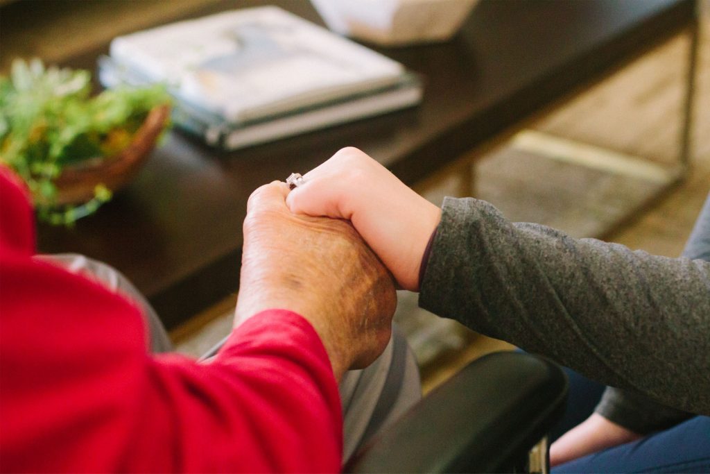Two people holding hands at a nursing home, Bailey Creek, where memory care is provided