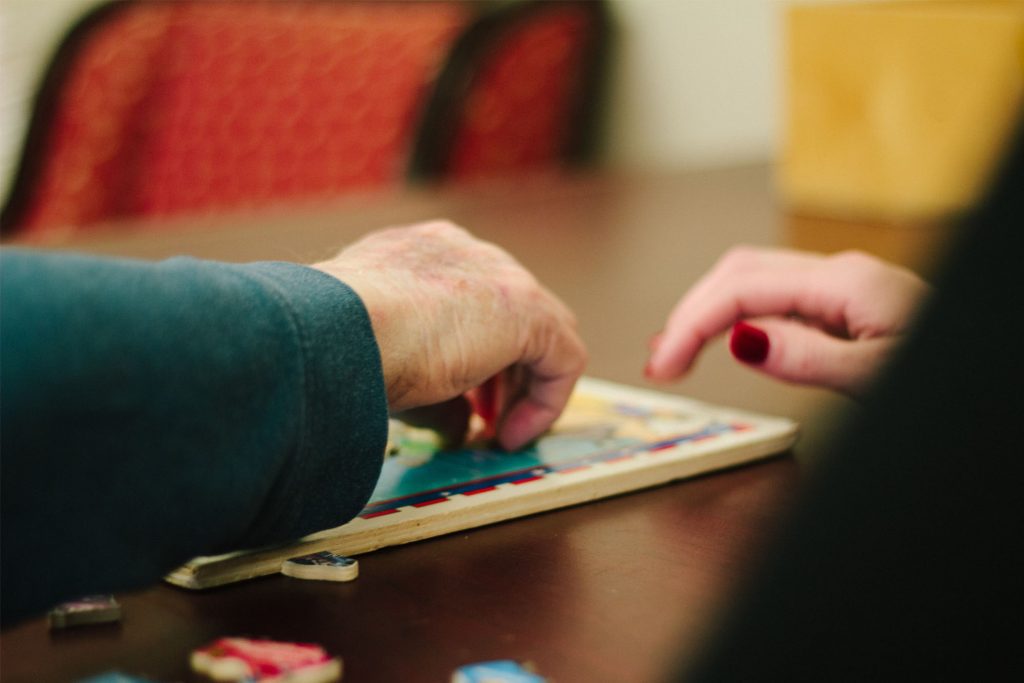 A memory care resident working with a nurse while doing a therapy activity