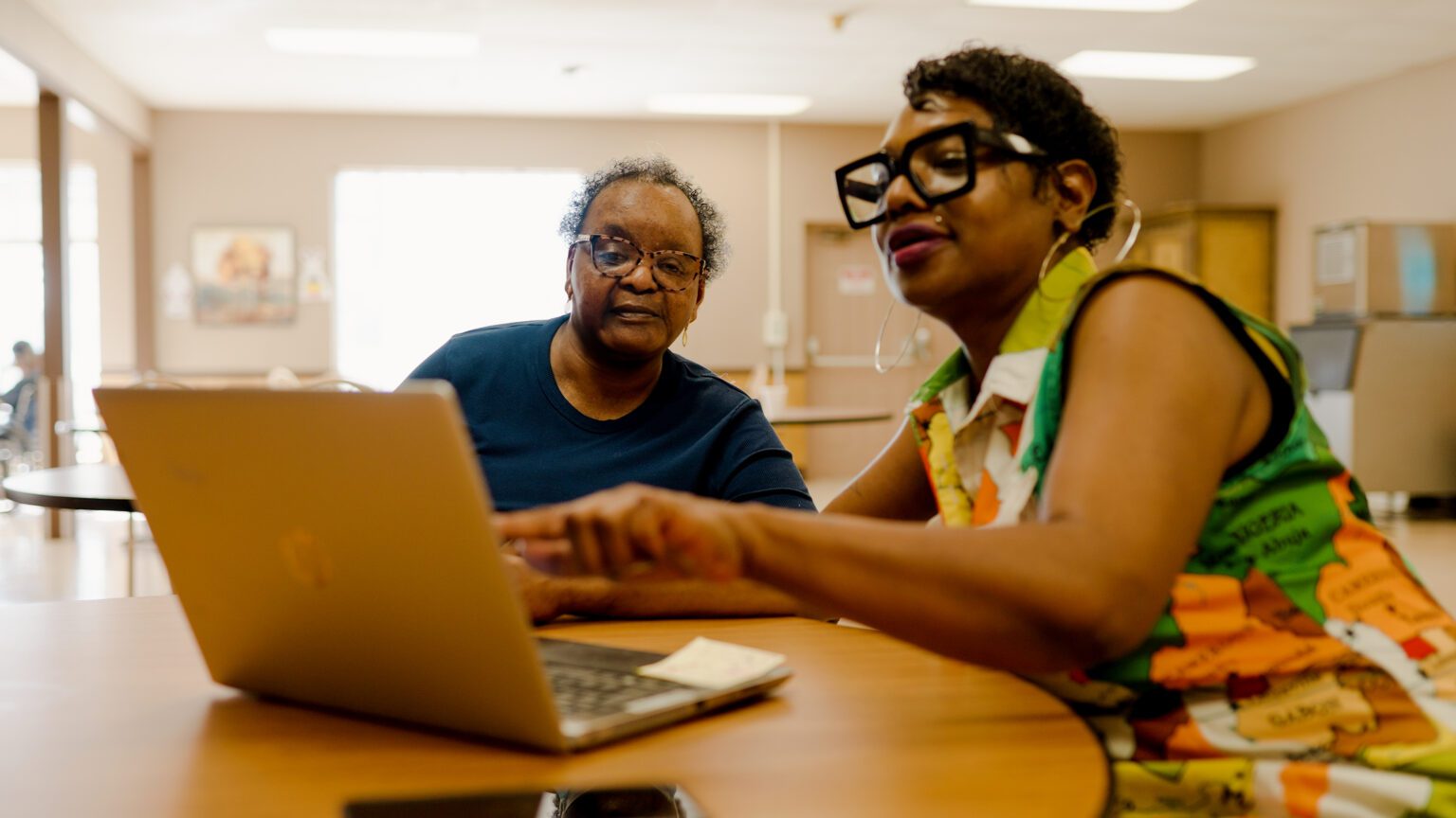 A woman and staff worker use the computer at a skilled nursing nursing home